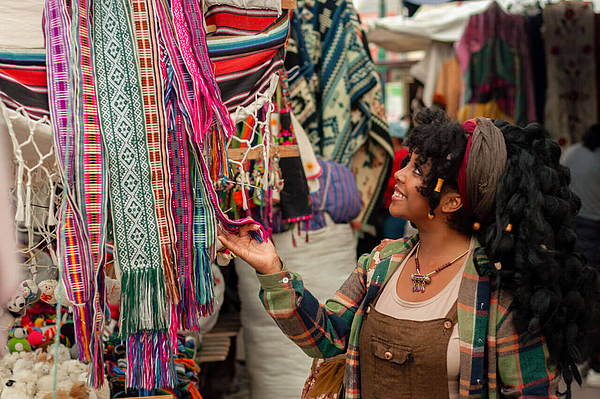 Touristin betrachtet bunte Stoffe auf Markt