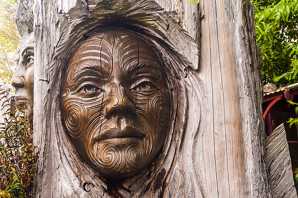 Detail einer Holzskulptur mit geschnitztem Gesicht.
