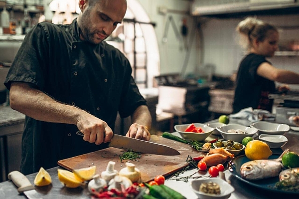 Koch bereitet frische Zutaten in maltesischer Küche zu.