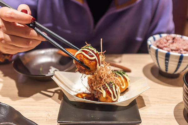 Takoyaki Streetfood wird mit Stäbchen