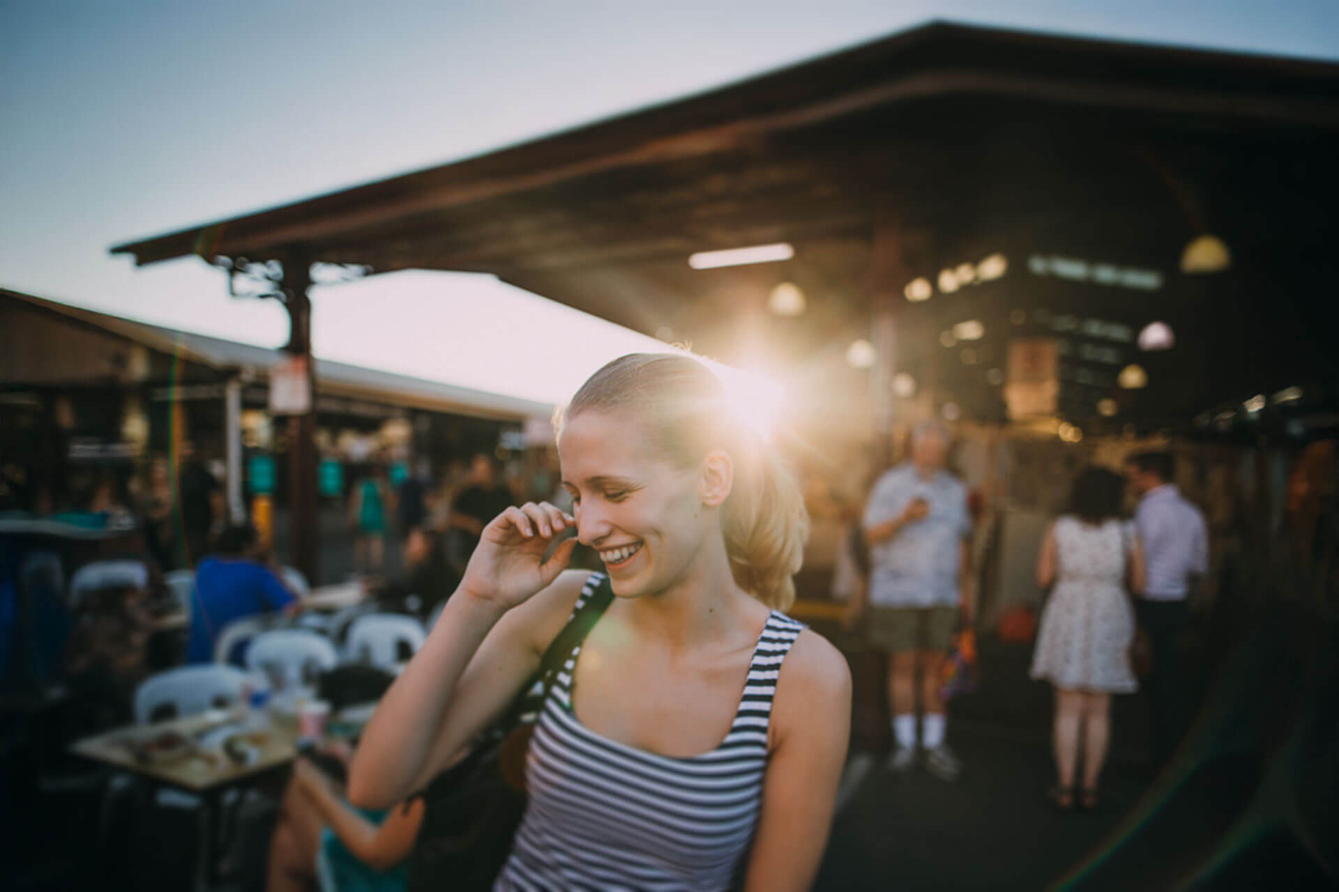 Lachende Person genießt den Abend auf einem belebten Markt in Melbourne bei Sonnenuntergang