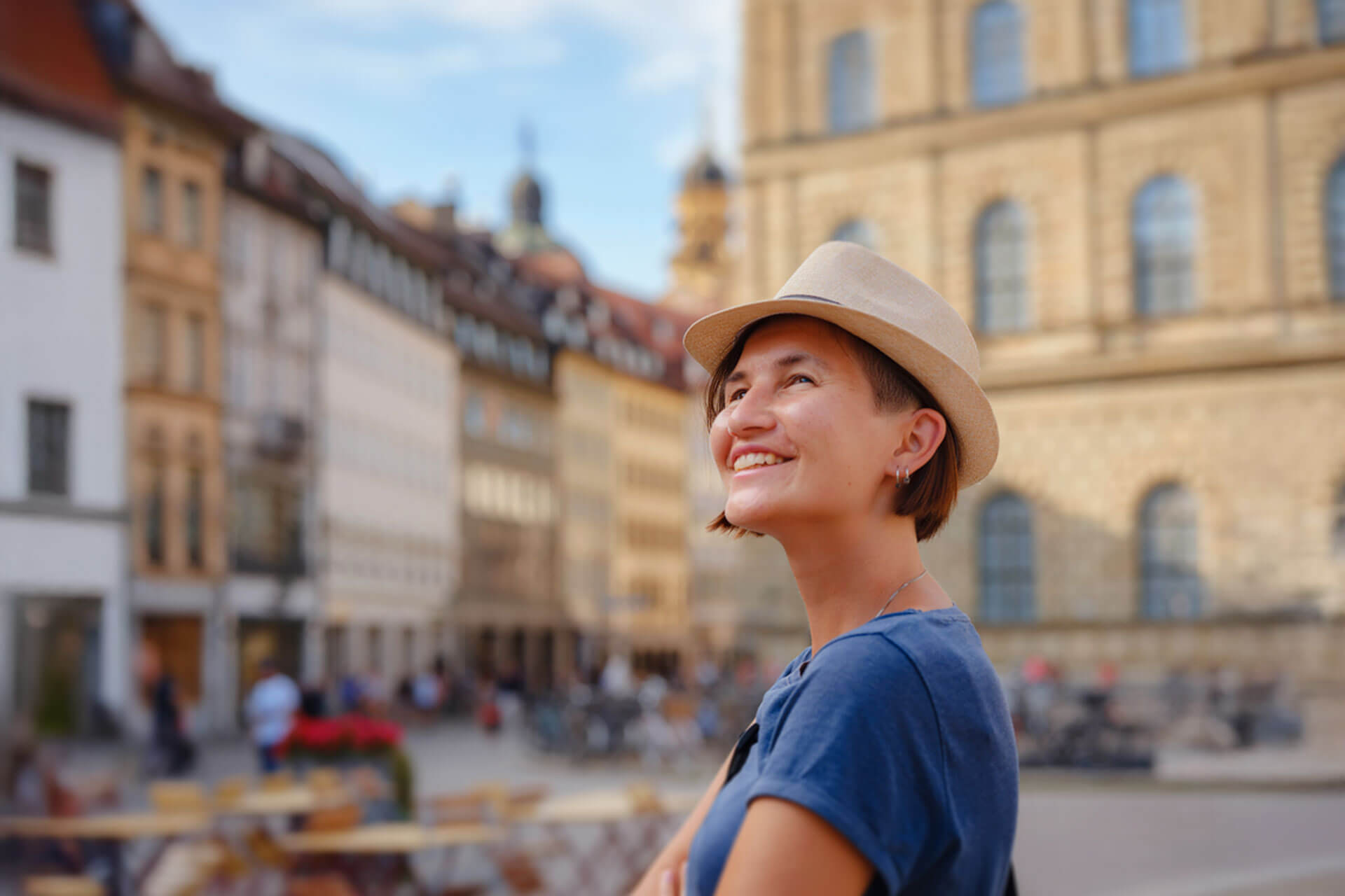 Lächelnde Person mit Hut genießt den sonnigen Tag in der Altstadt von Freiburg