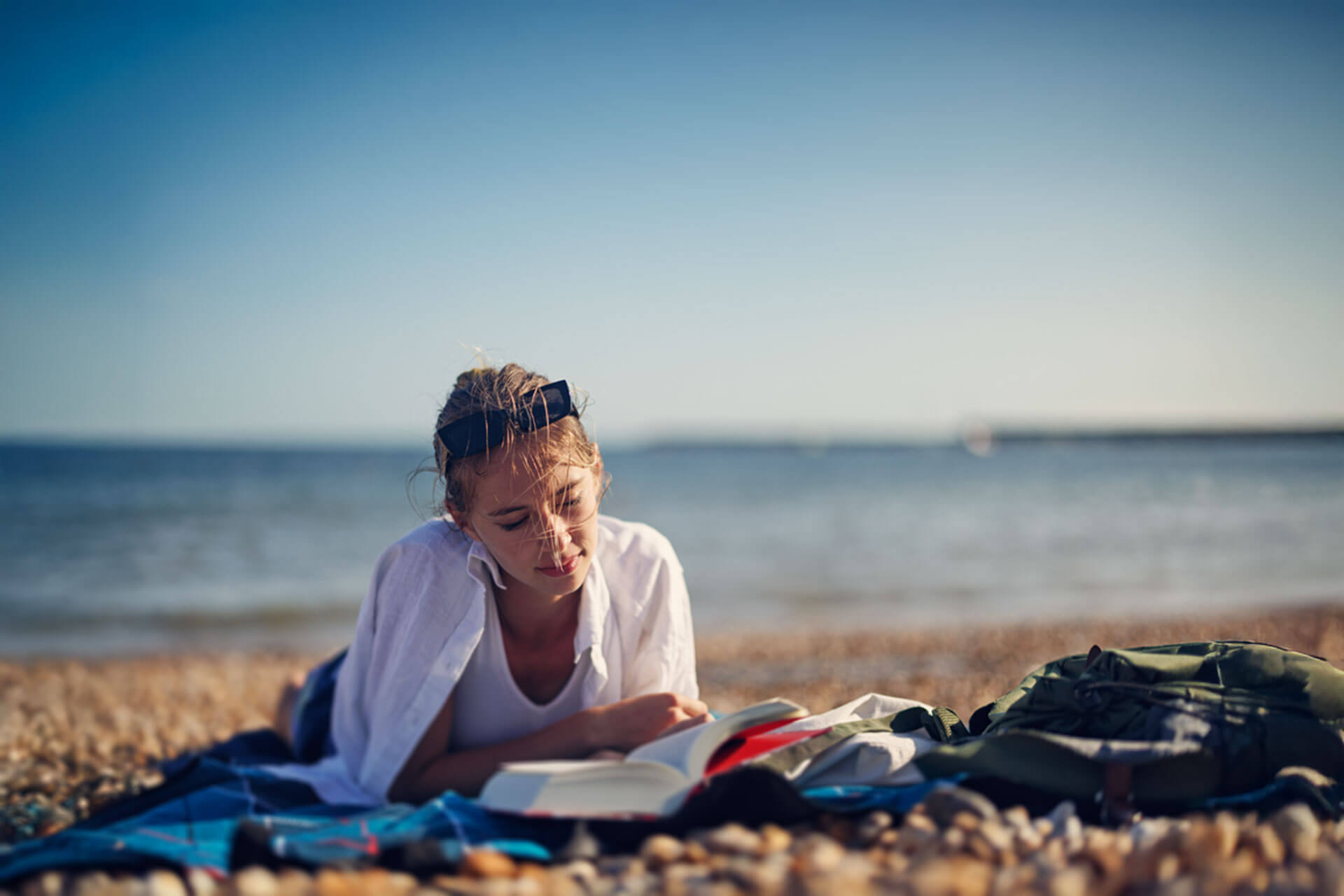 Lesende Person am Strand während einer Englisch Sprachreise, entspanntes Lernen im Freien