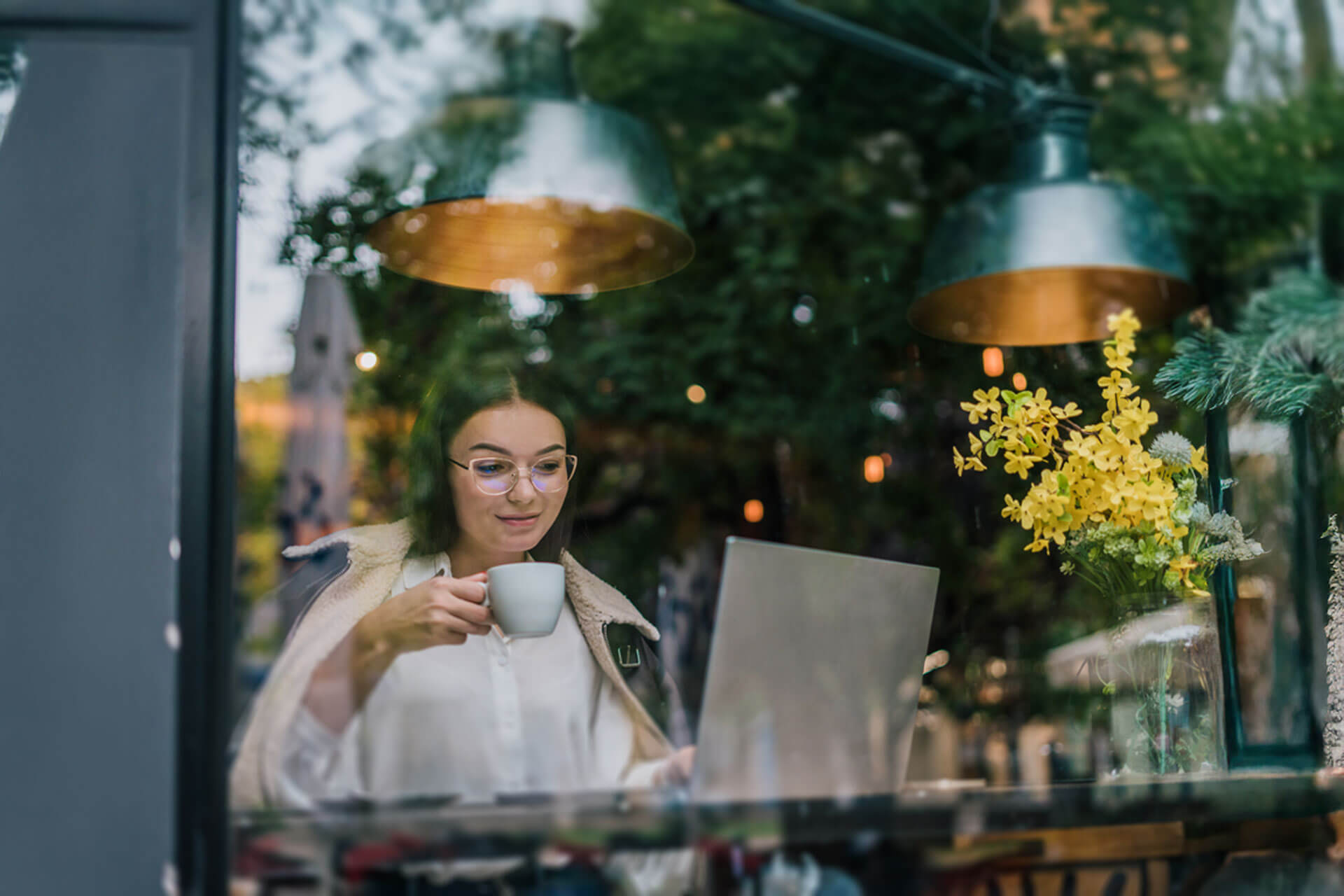 Teilnehmerin einer Englisch Sprachreise lernt online bei Kaffee im gemütlichen Lokal