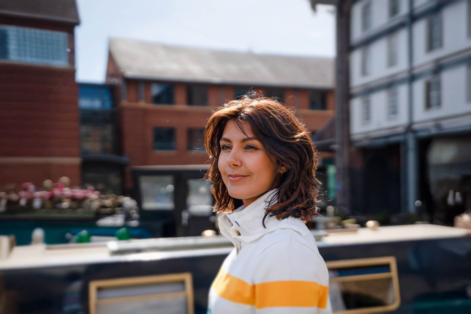 Frau spaziert entspannt an den Docks von Liverpool entlang, im Hintergrund moderne Backsteinarchitektur