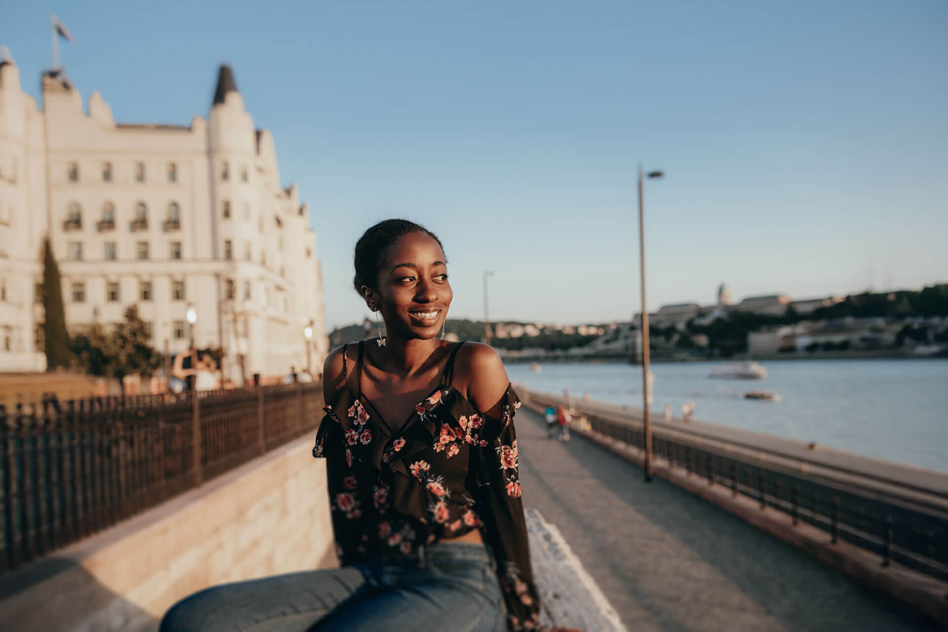 Lächelnde Sprachreisende am Flussufer übt Englischkonversation während ihres Sprachkurses im Ausland