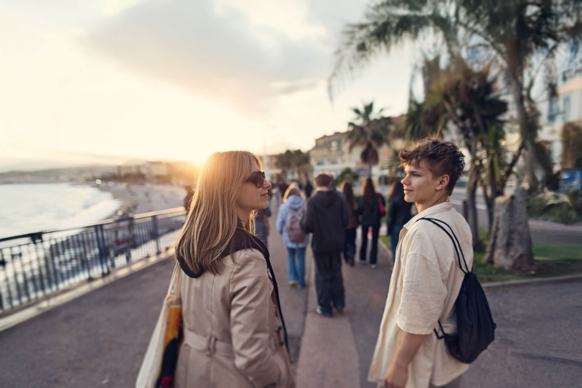 Jugendliche spazieren bei Sonnenuntergang entlang der Promenade in Cannes