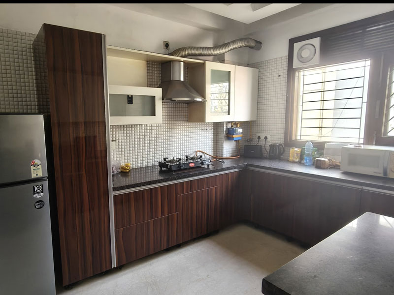 Voll ausgestattete Küche im Apartment in Neu-Delhi mit Herd, Kühlschrank und Arbeitsfläche.