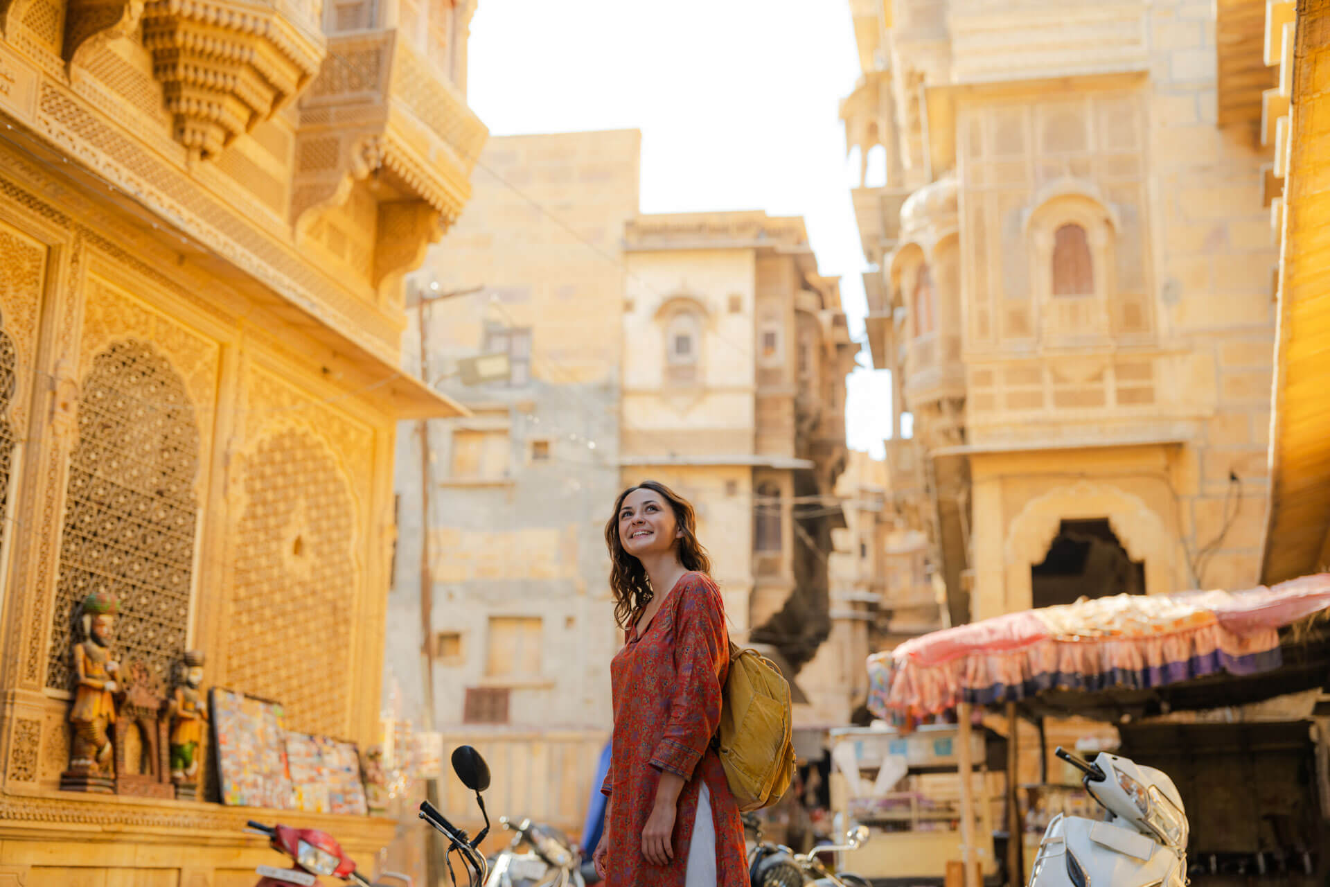 Person erkundet eine sonnige Altstadtgasse in Neu-Delhi mit traditioneller Sandsteinarchitektur