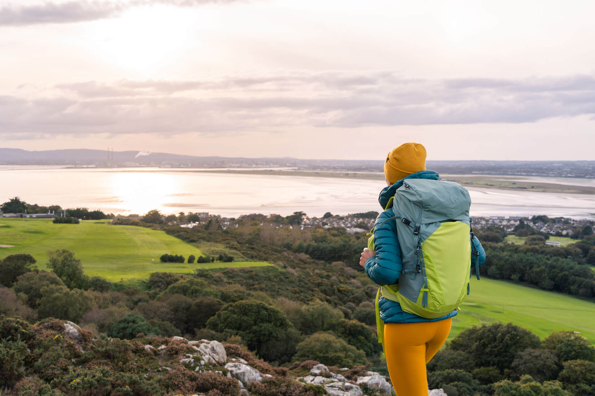 Blick auf die Küste bei Dublin mit wandernder Person im Abendlicht