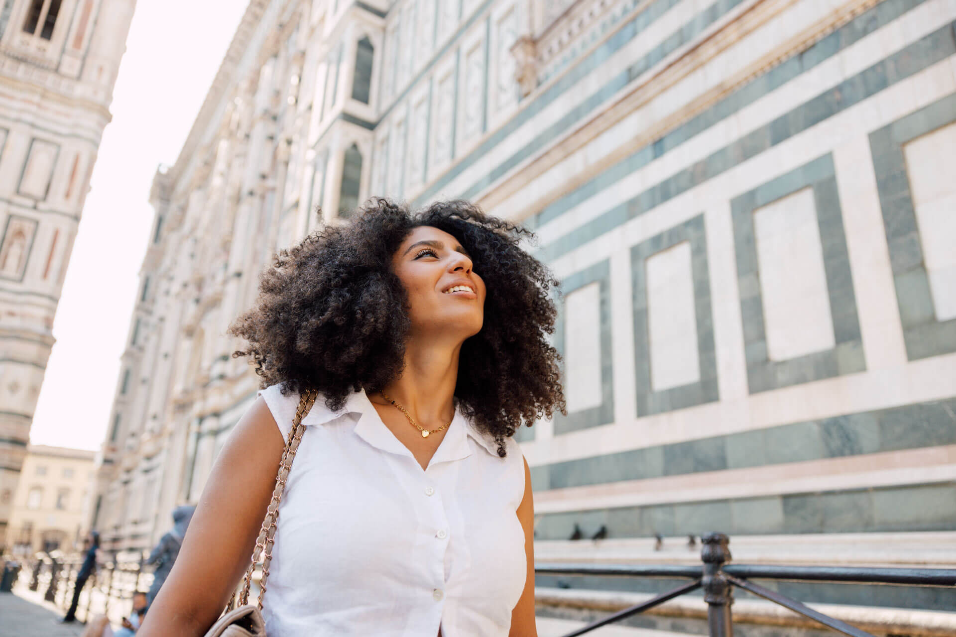 Frau spaziert lächelnd durch das historische Zentrum von Florenz vor der Fassade des Doms