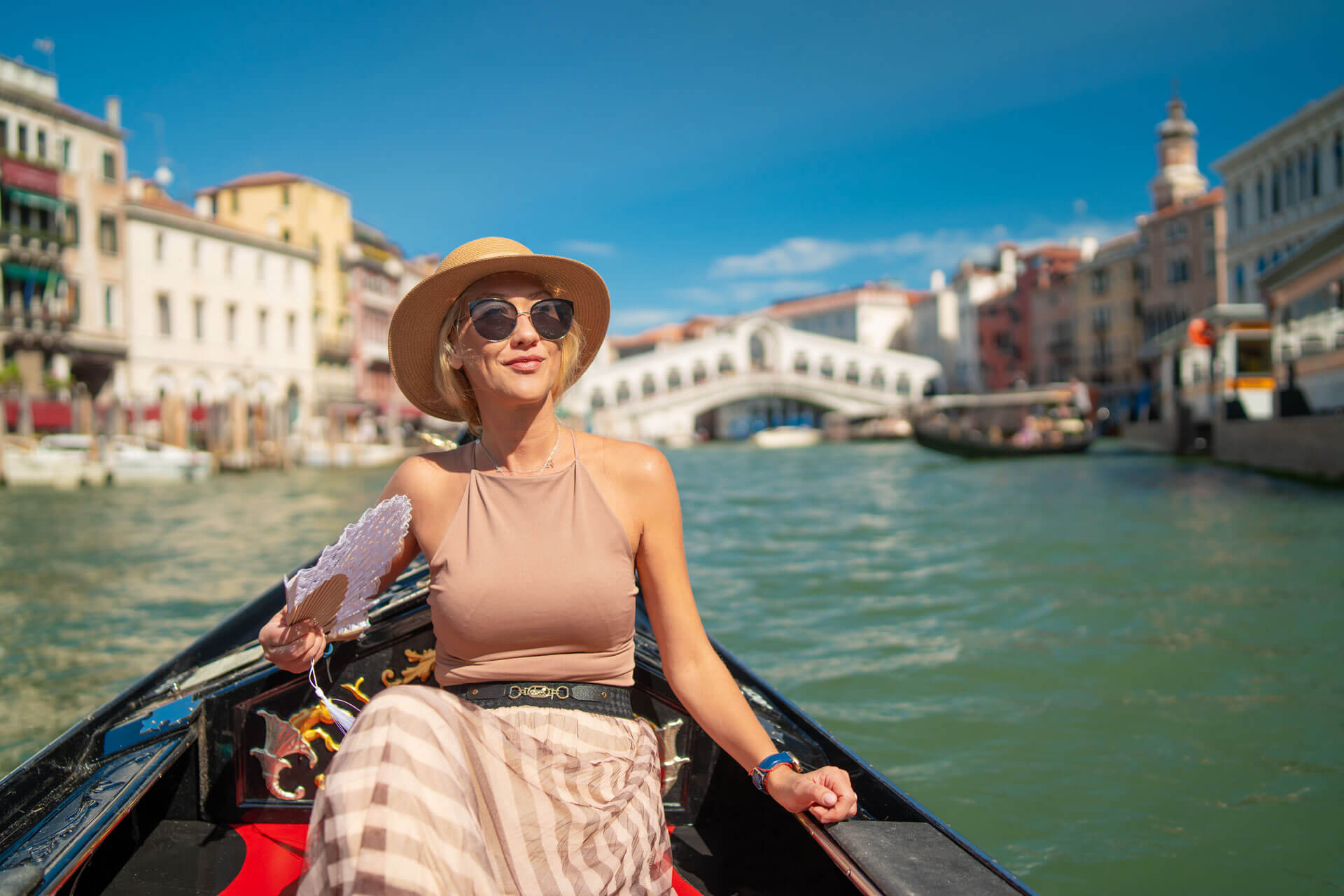 Frau genießt eine Gondelfahrt auf dem Canal Grande in Venedig mit Blick auf die Rialtobrücke