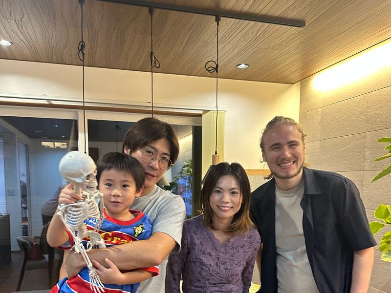 Schüler mit seiner japanischen Gastfamilie in Tokio, gemeinsam lachend in einem gemütlichen Wohnzimmer.