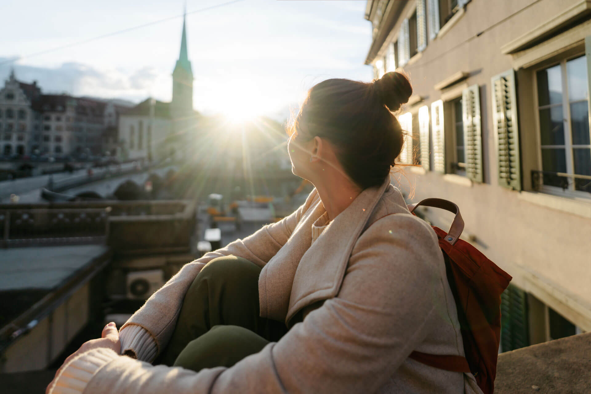 Person blickt bei Sonnenuntergang über die Dächer von Zürich in Richtung Altstadt