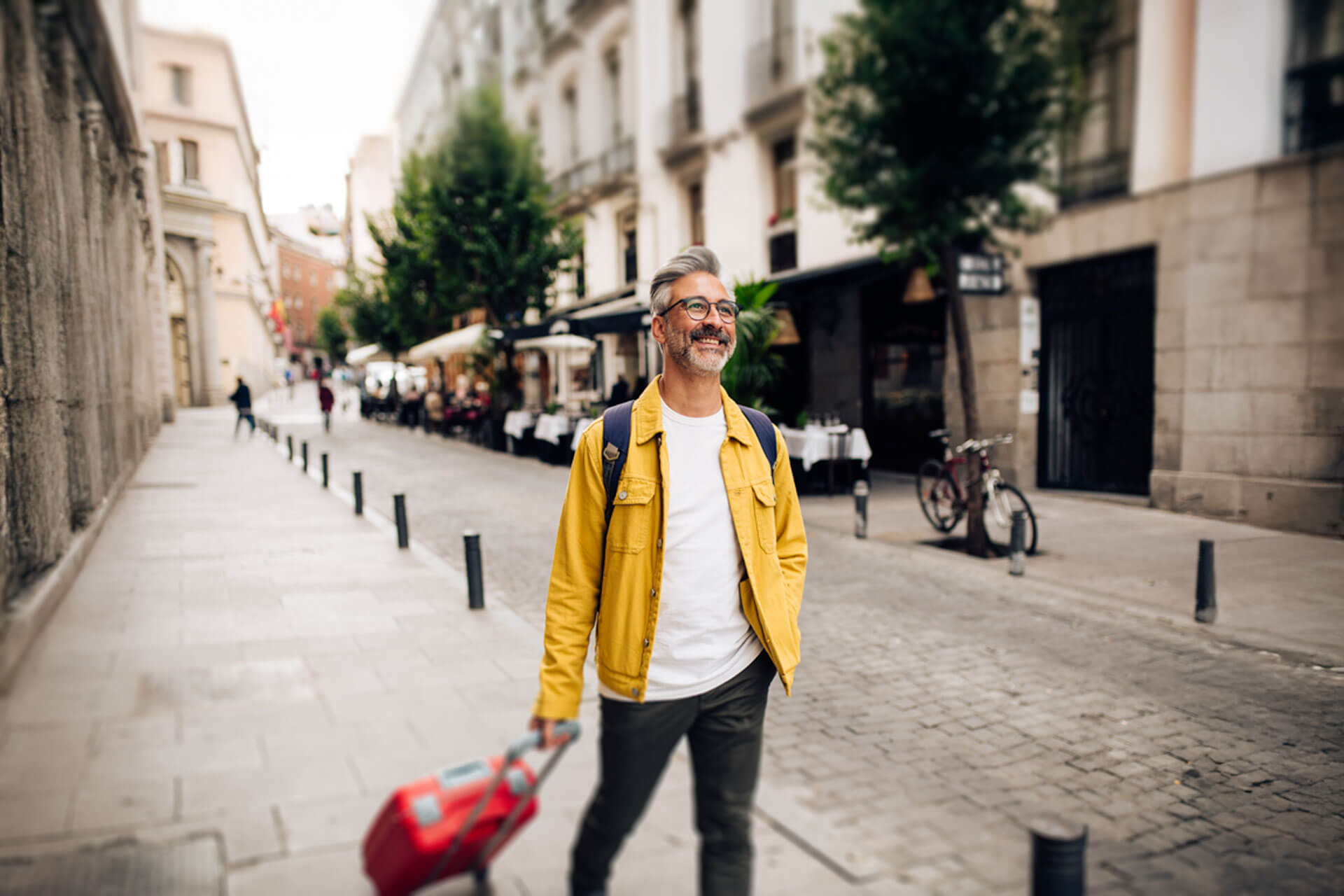 Reisender mit Koffer in Stadtgasse, Anreise zur Sprachreise, Konversation und Hörverstehen unterwegs üben.
