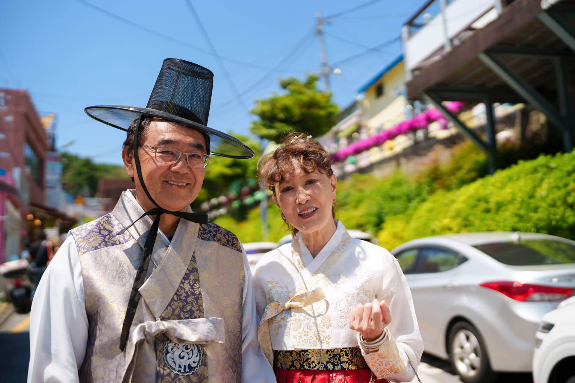 Zwei Personen in traditioneller koreanischer Kleidung posieren auf einer sonnigen Straße in Busan
