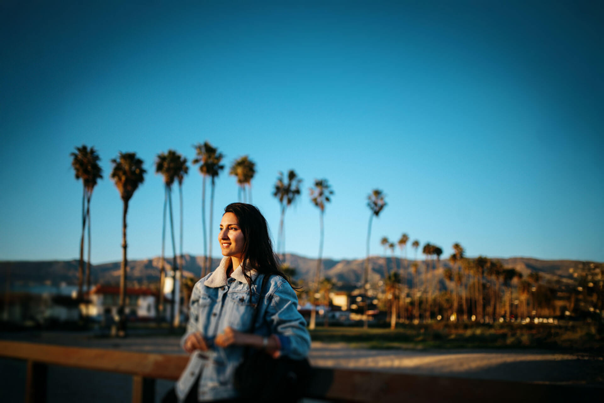 Person genießt den Sonnenuntergang an der Promenade von Santa Barbara mit Palmen und Bergen im Hintergrund