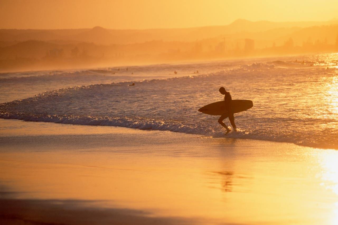Surfer im Abendlicht an der Gold Coast, Aussprache verbessern im Sprachkurs am Strand.