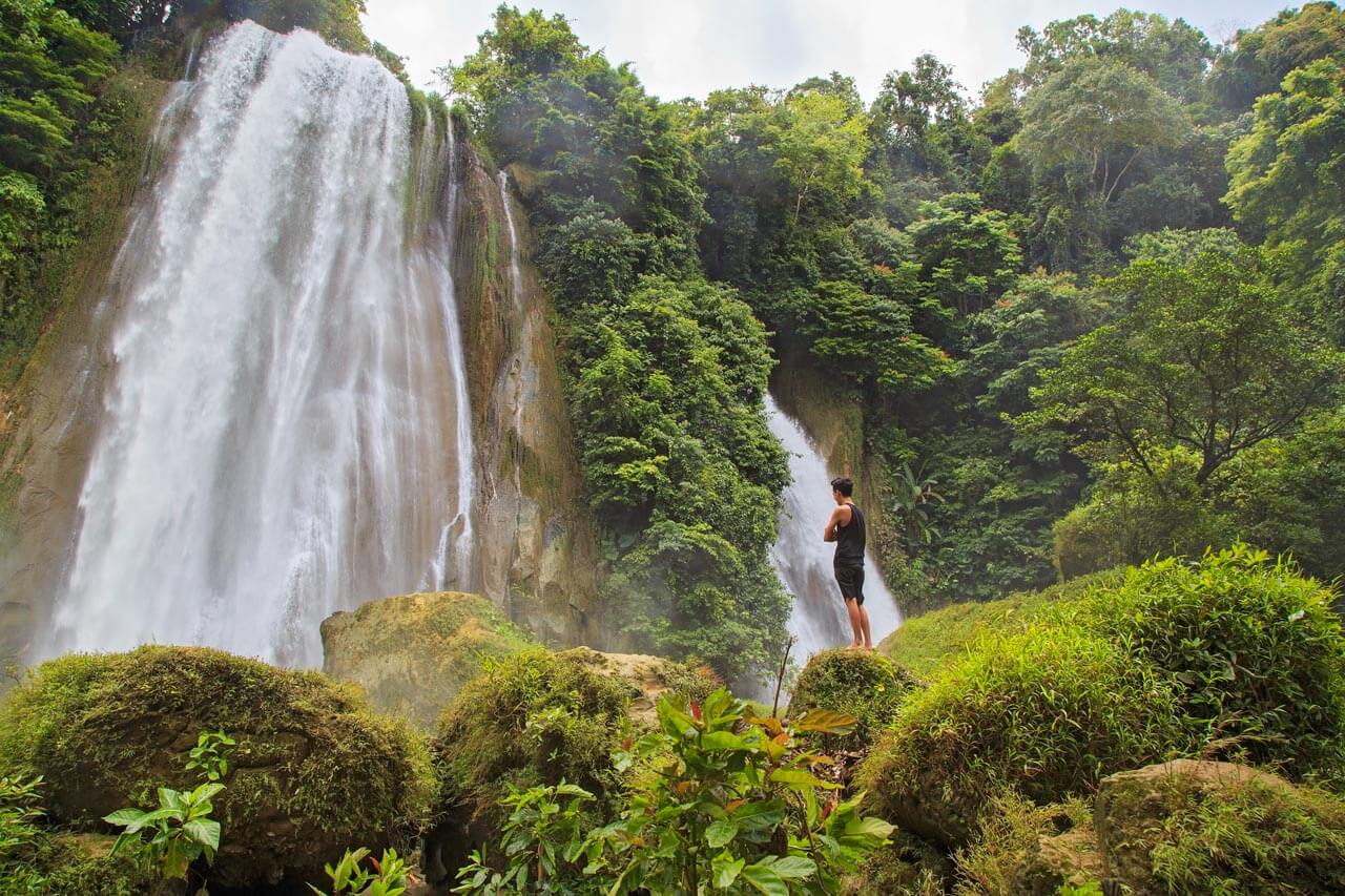 Hoher Wasserfall im dichten Regenwald, feiner Sprühnebel in der Luft. Grammatik trainieren mit Naturbeschreibungen.