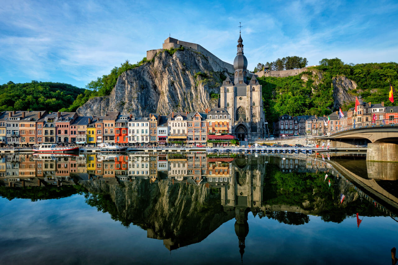 Dinant an der Maas: bunte Häuserzeile, Kollegiatkirche Notre-Dame und Festung auf dem Felsen, Spiegelung im Wasser