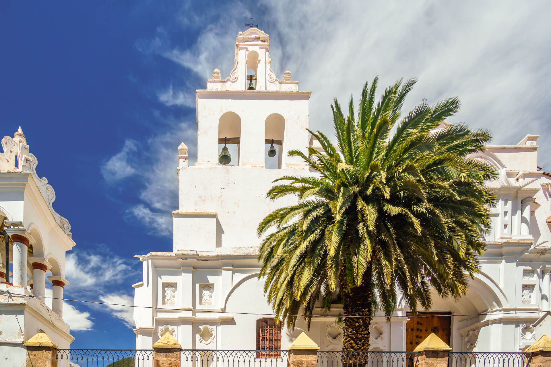 Weiße Kirchenfassade mit Palmen in Sucre Sprachreise Bolivien Grammatik üben