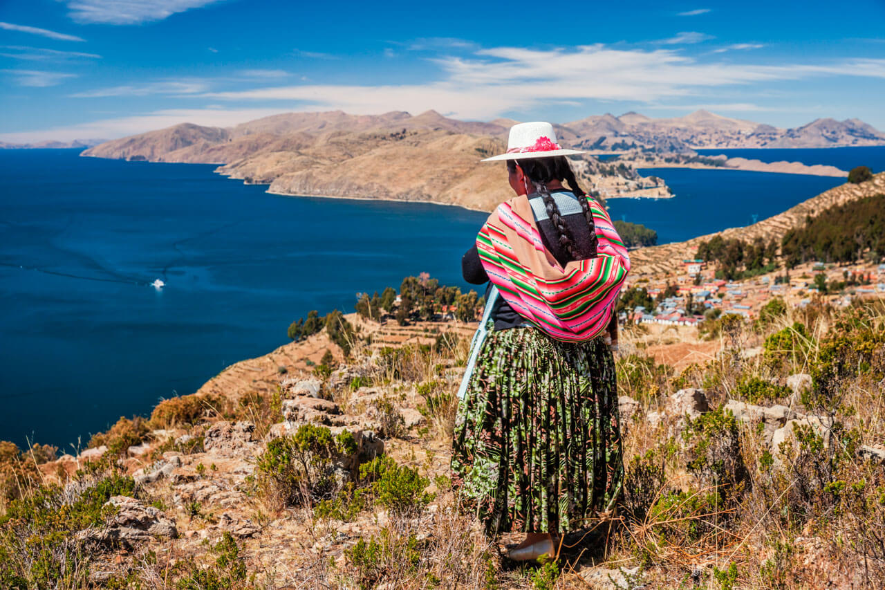 Frau mit traditioneller Kleidung blickt über den Titicacasee Sprachreise Bolivien Konversation im Alltag
