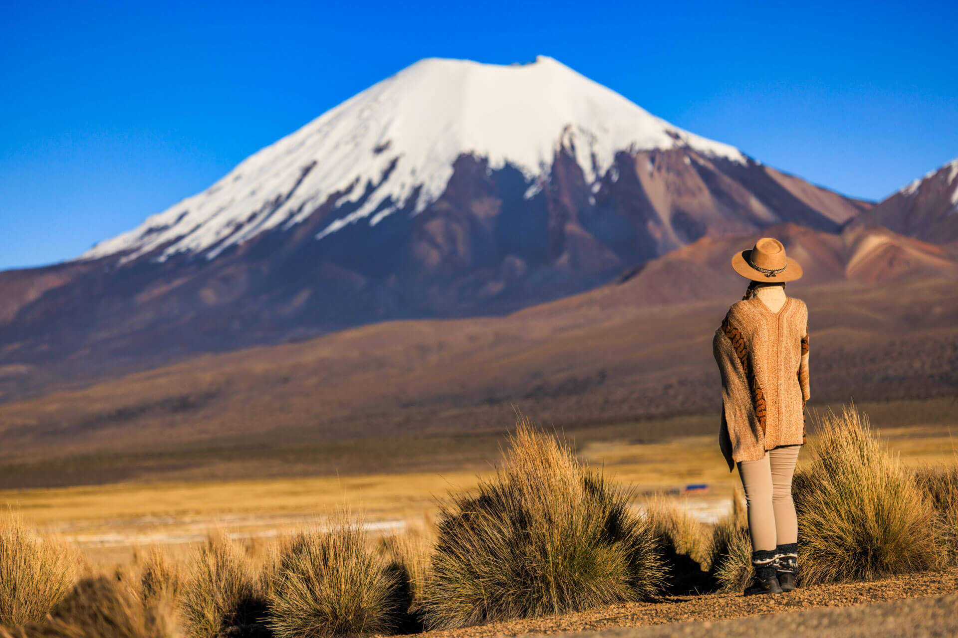 Frau in traditioneller Kleidung vor schneebedecktem Vulkan Sprachreise Bolivien Grammatik üben