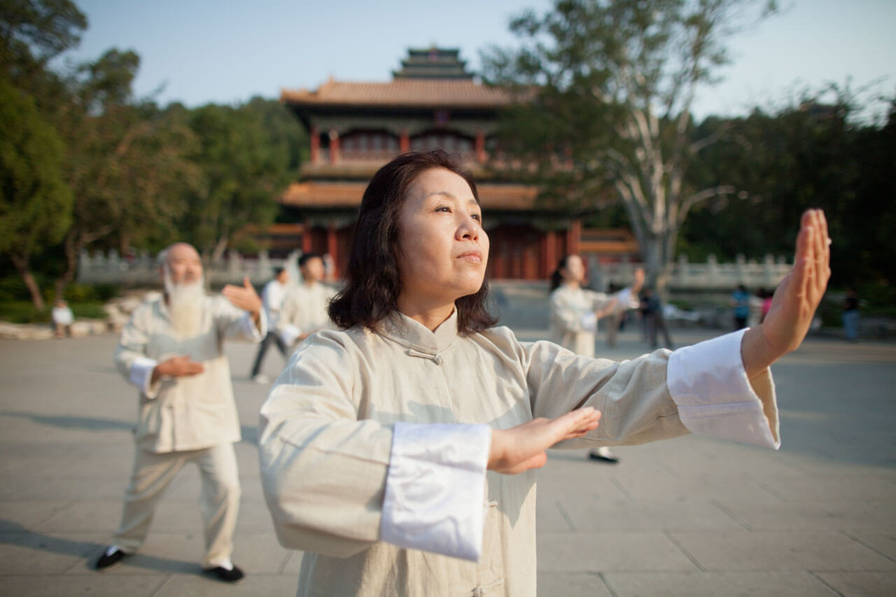 Frau praktiziert Tai Chi im Tempelpark von Peking am Morgen