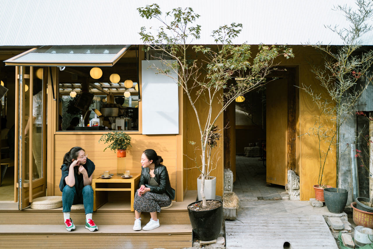 Zwei Frauen vor einem Hutong Café in Peking bei Kaffee und Gespräch