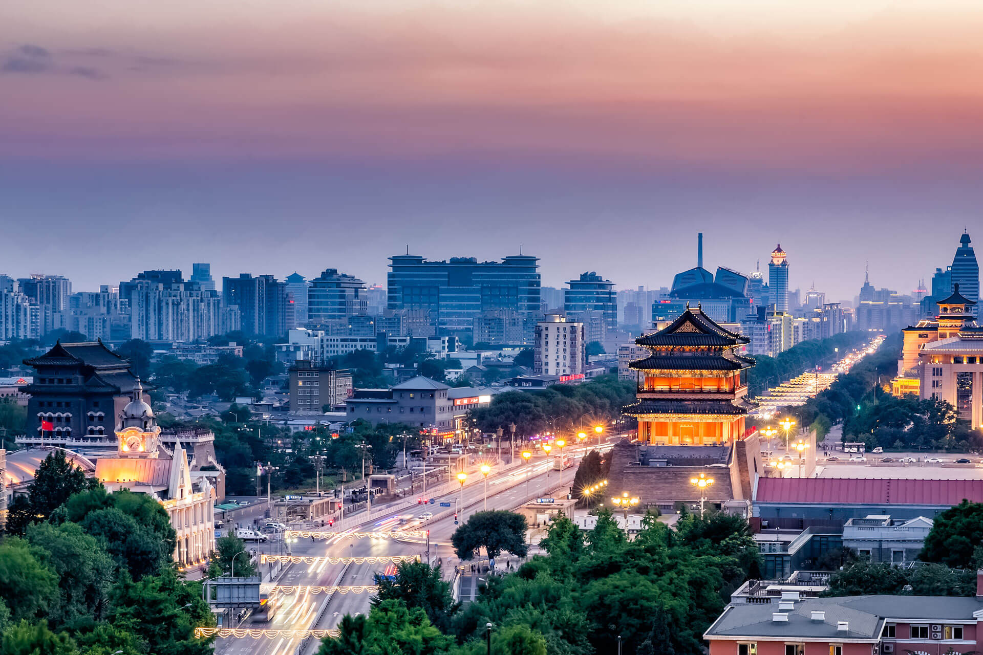 Peking Skyline bei Abenddämmerung mit beleuchtetem historischem Tor und Lichtspuren entlang der Chang’an Avenue