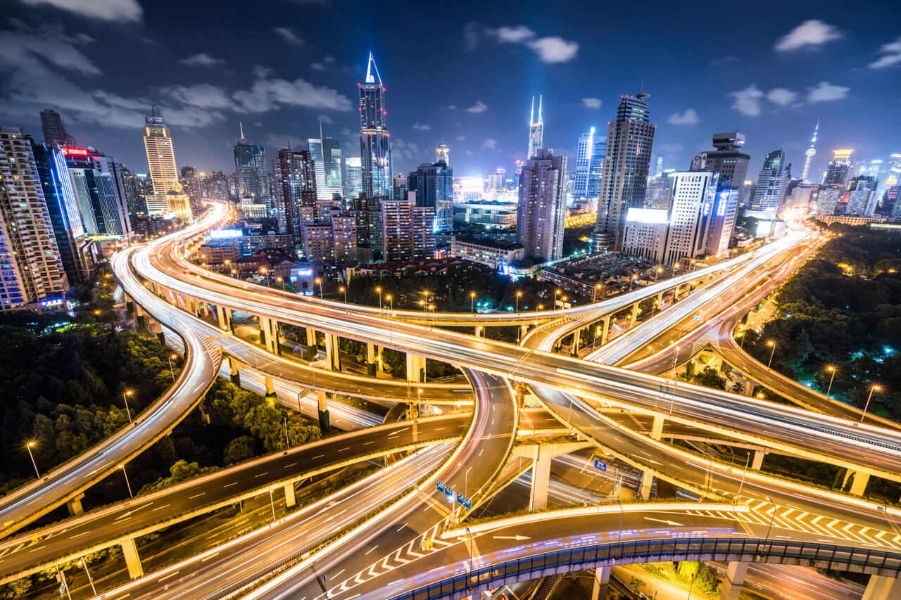 Shanghai Hochstraßenkreuz bei Nacht mit Lichtspuren und Wolkenkratzern