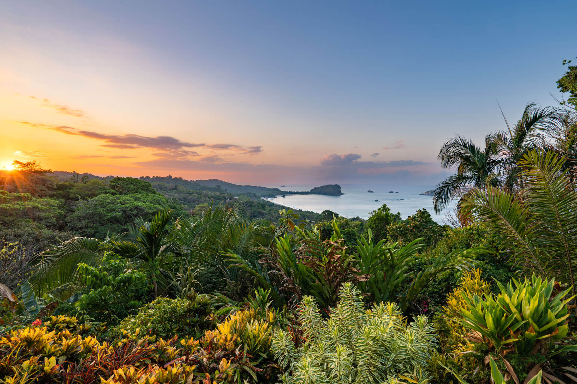 Sonnenuntergang über tropischem Regenwald mit Blick aufs Meer Sprachreise in die Natur