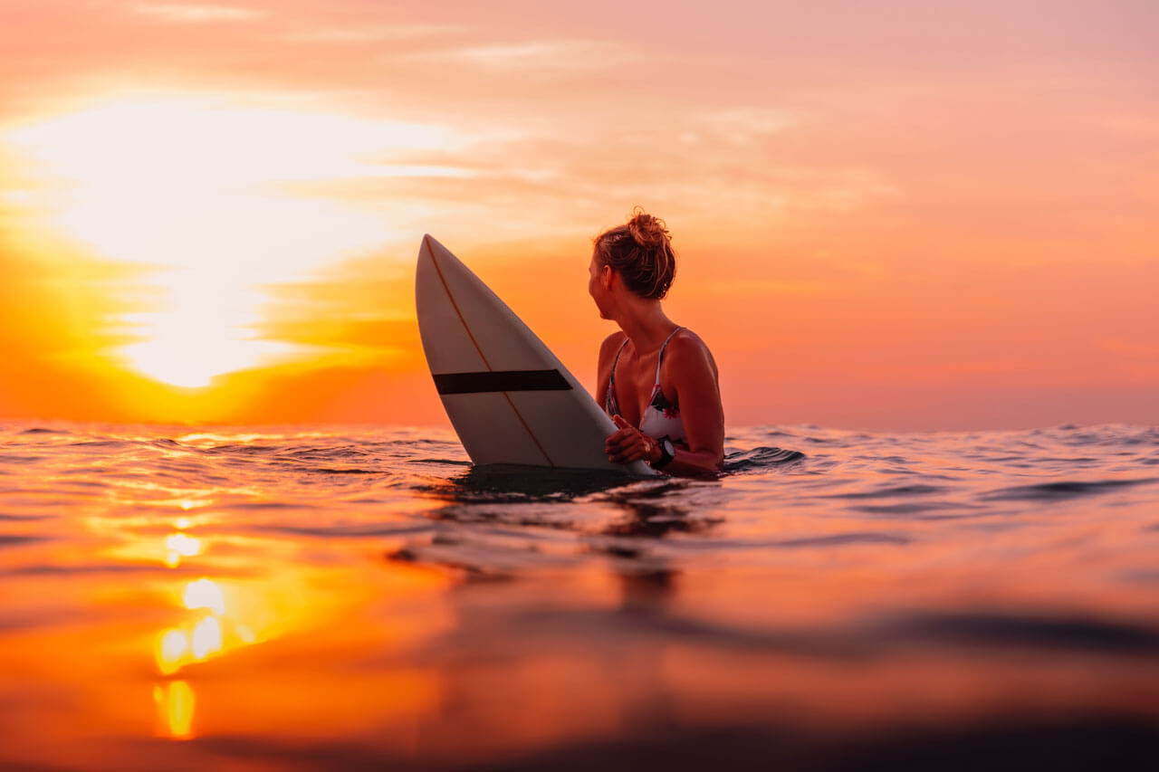 Surferin im Meer beim Sonnenuntergang Sprachreise mit Hörverstehen in freier Natur