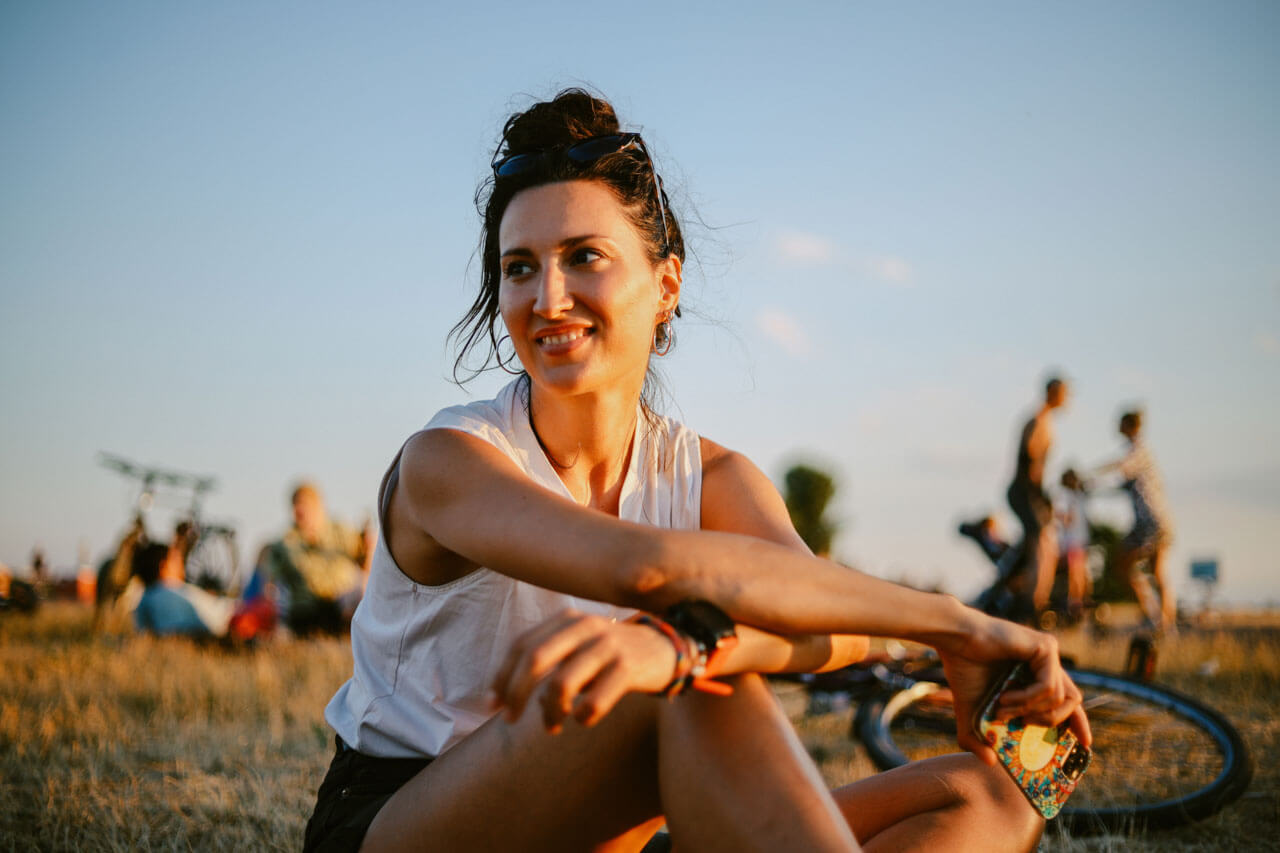 Junge Frau entspannt im Abendlicht auf dem Tempelhofer Feld, Fahrrad im Hintergrund.