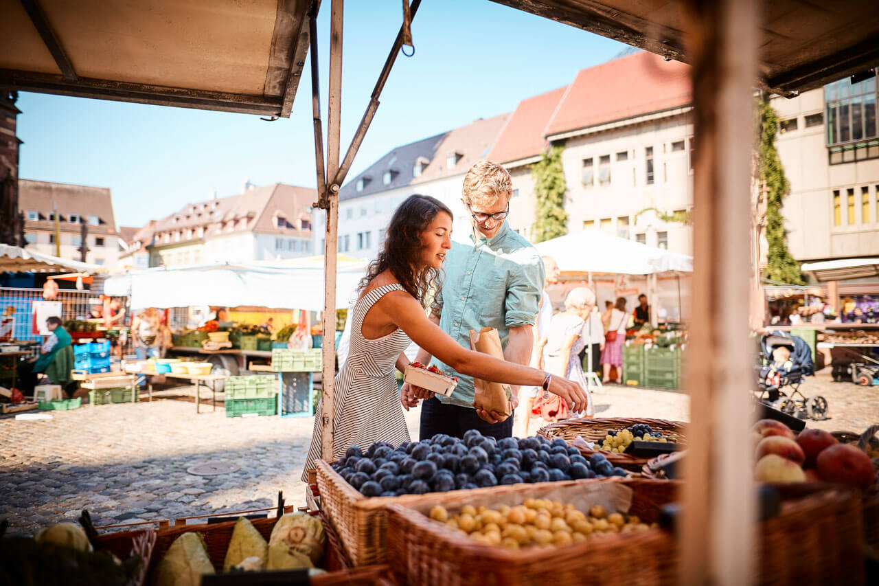 Paar kauft frisches Obst auf dem Freiburger Münstermarkt im Sommer.