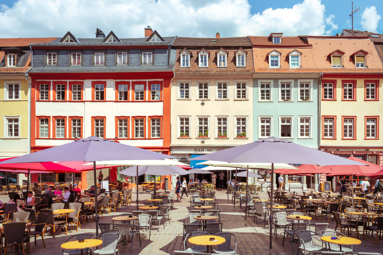 Bunte Fassaden und Straßencafés mit Sonnenschirmen auf einem gemütlichen Platz
