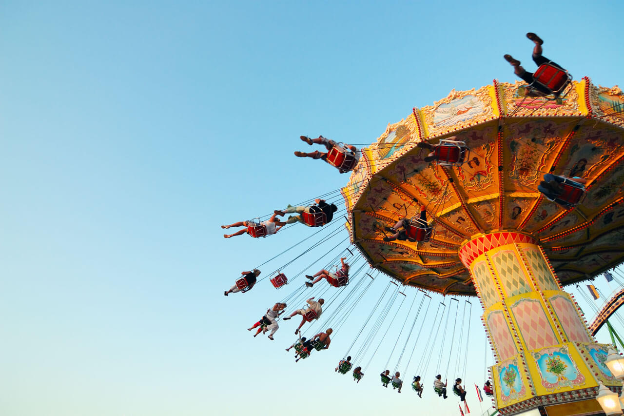 Kettenkarussell in Bewegung auf einem Volksfest vor blauem Himmel.