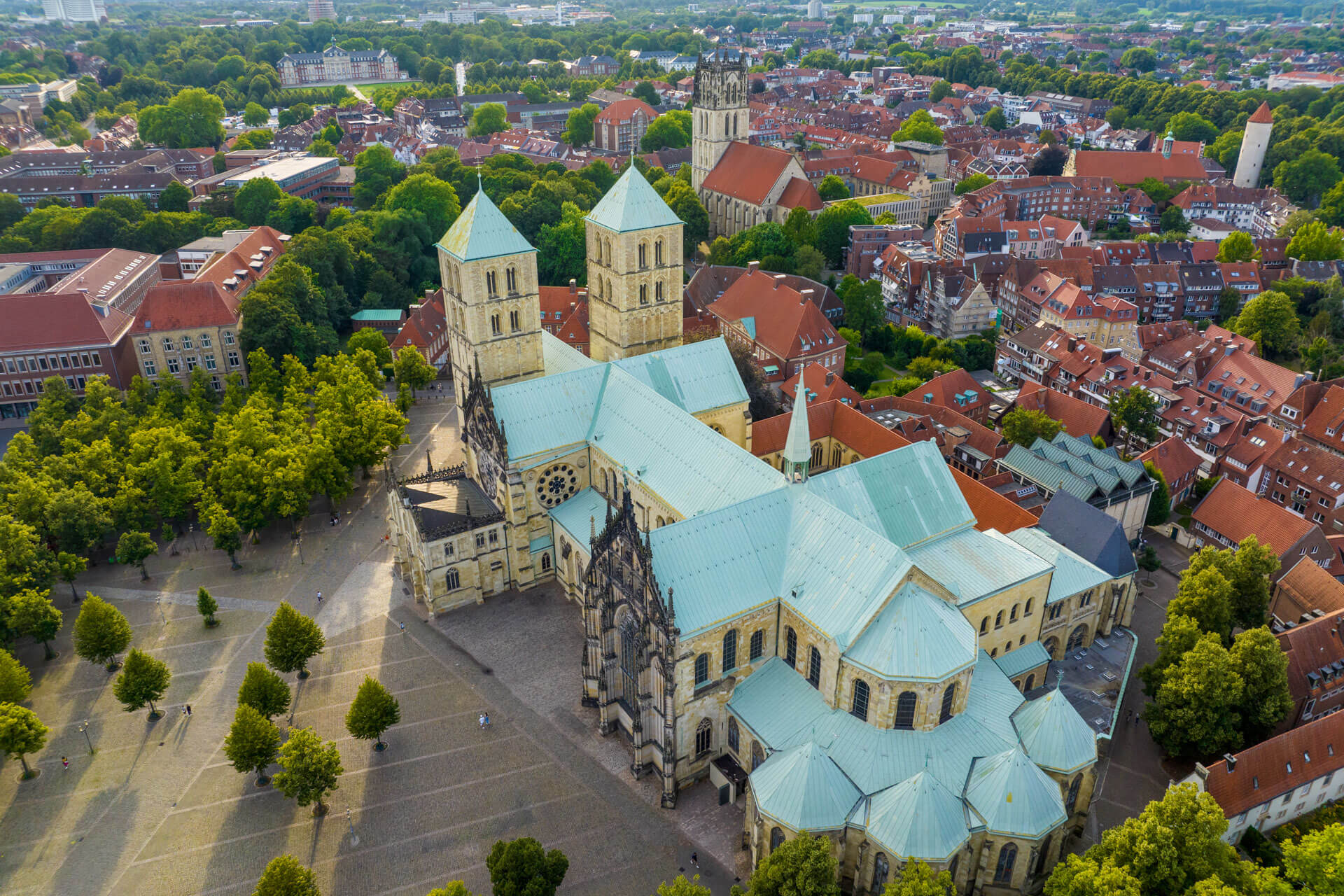 Luftaufnahme des St.-Paulus-Doms mit grünem Domplatz und roten Dächern der Altstadt.