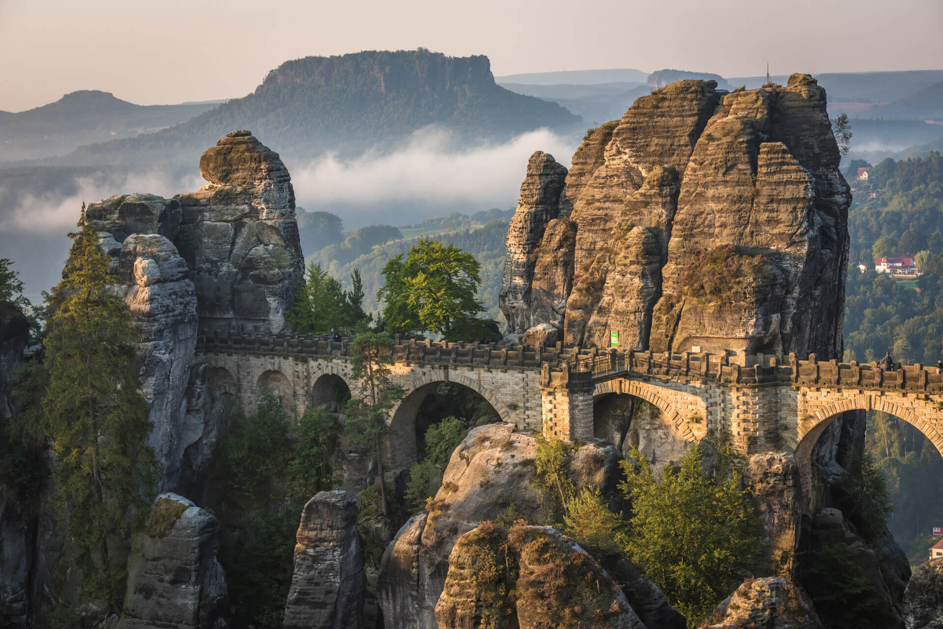 Die Basteibrücke in der Sächsischen Schweiz, umgeben von Felsen und Morgennebel.