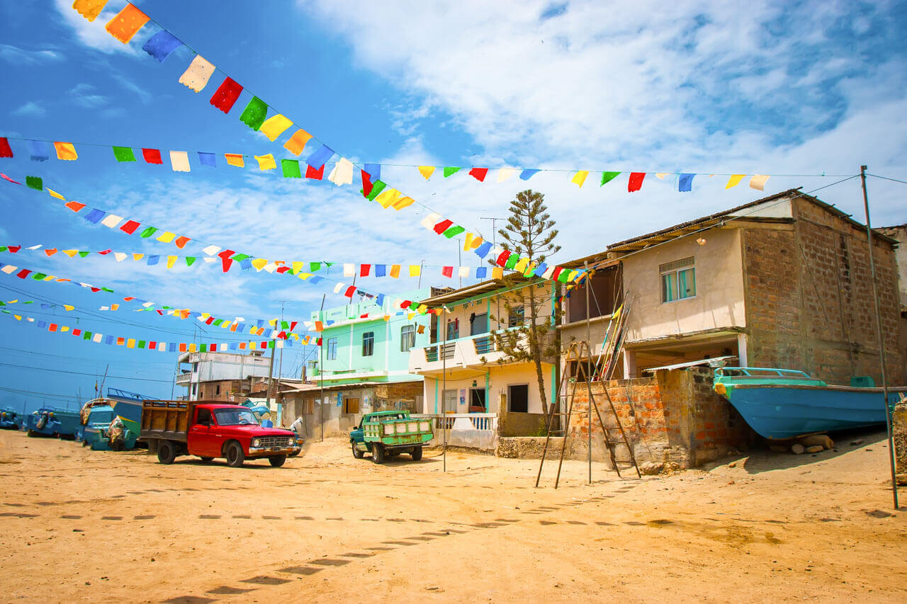 Straßenbild des Fischerdorfs Montañita mit bunten Wimpeln und einfachen Häusern in Ecuador