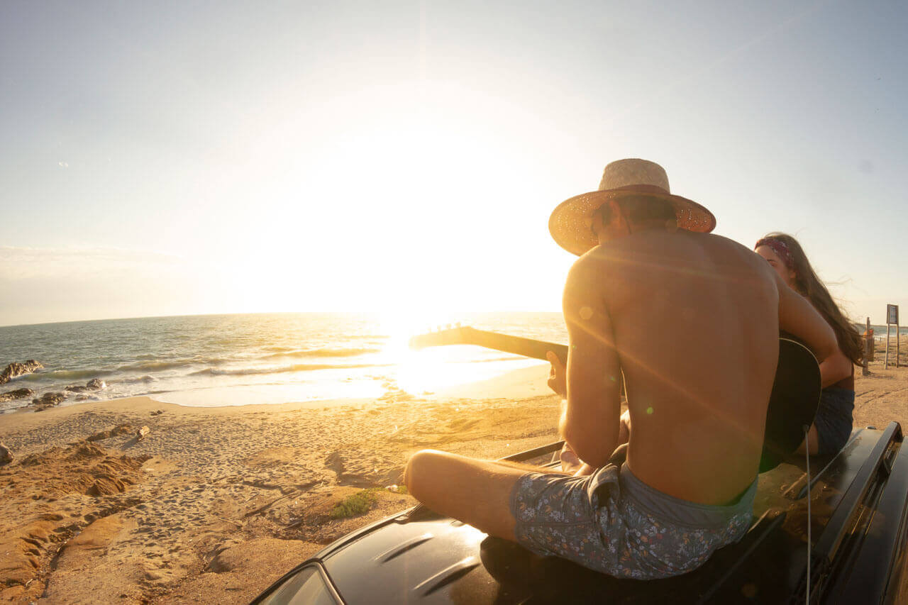 Zwei Personen spielen Gitarre am Strand von Montañita und genießen den Sonnenuntergang in Ecuador