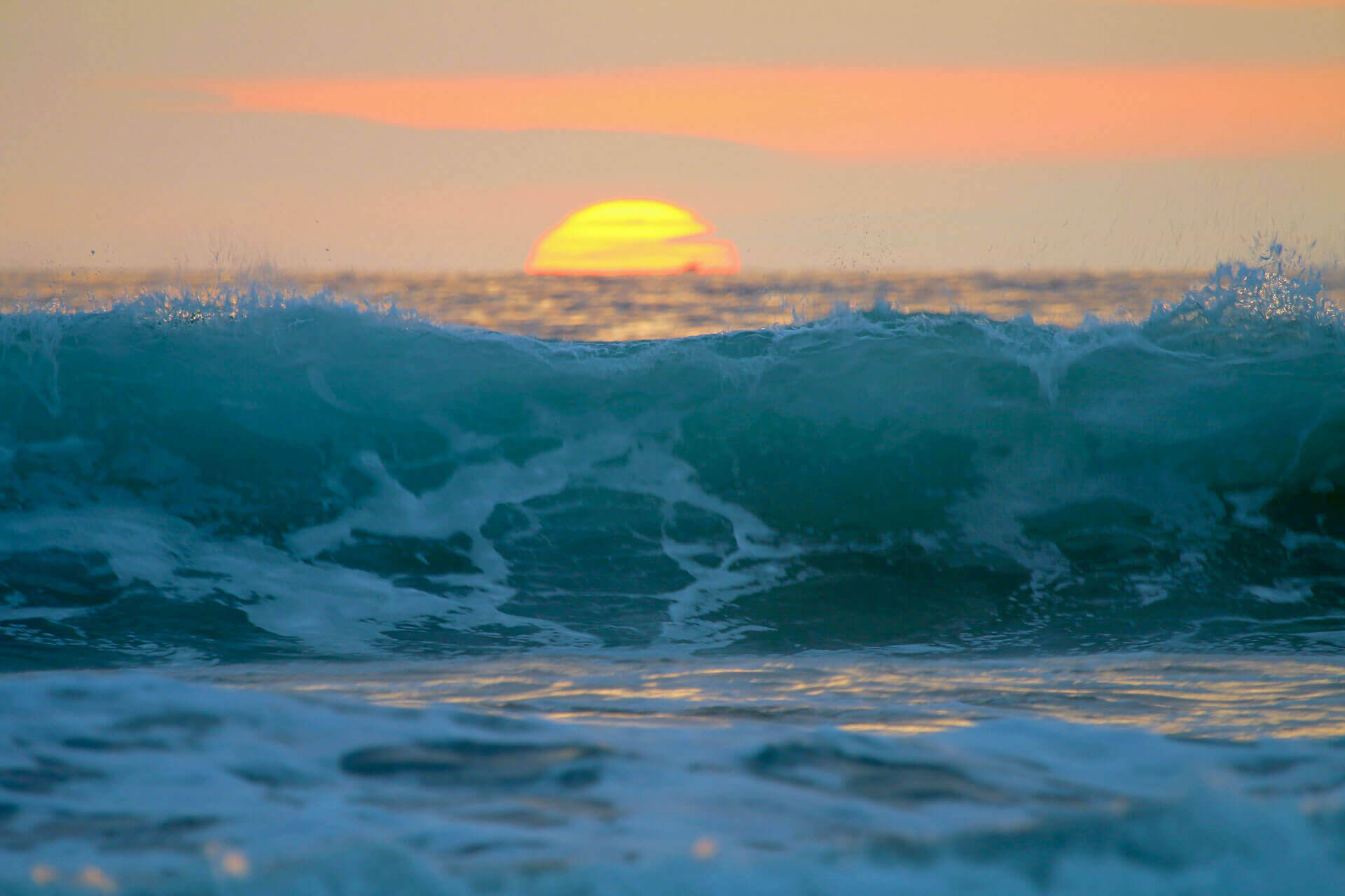 Sonnenuntergang über dem Pazifik mit hoher Welle vor Montañita an der Küste Ecuadors