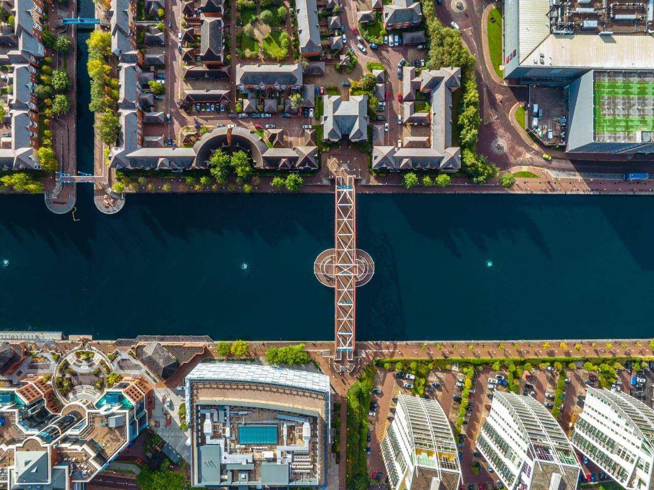 Drohnenaufnahme von Kanal, Brücke und moderner Wohnarchitektur in Manchester Präpositionen des Ortes und Raumvokabular trainieren im Englischkurs