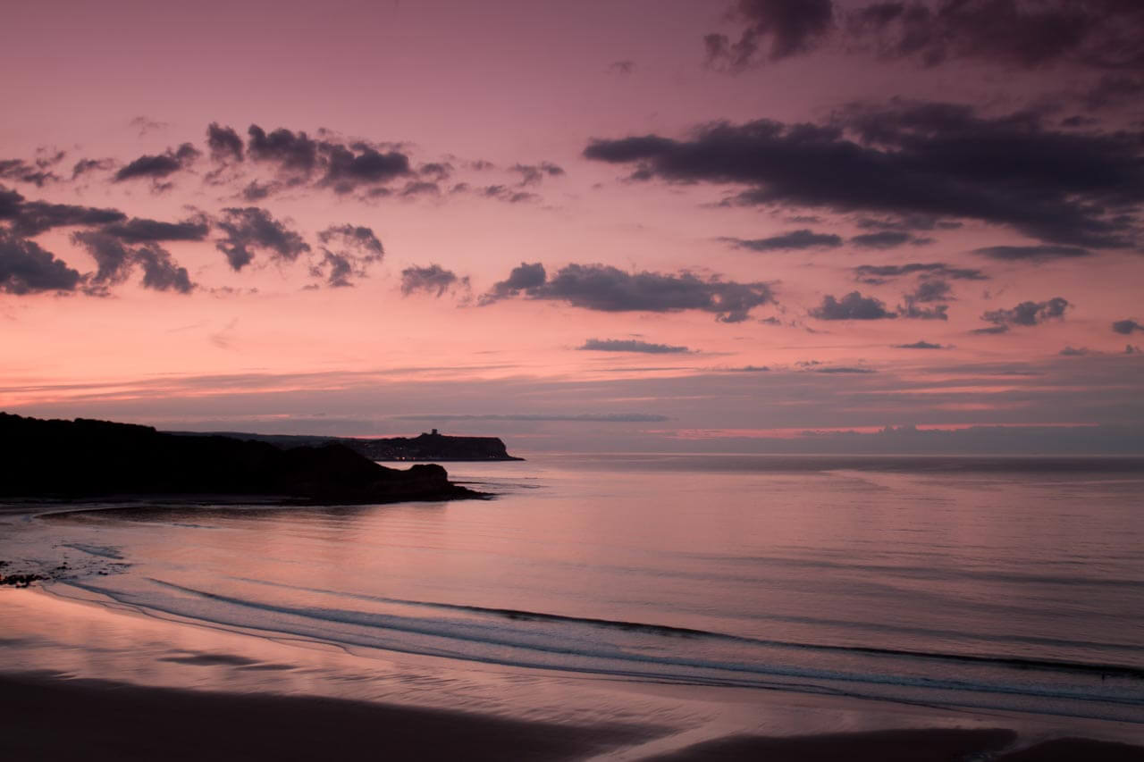 Cayton Bay bei Scarborough im rosa Abendhimmel mit ruhiger See Bildbeschreibung auf Englisch üben