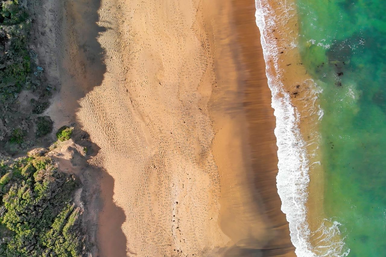 Leerer Sandstrand aus der Vogelperspektive mit sanften Wellen Hörverstehen üben am Meer
