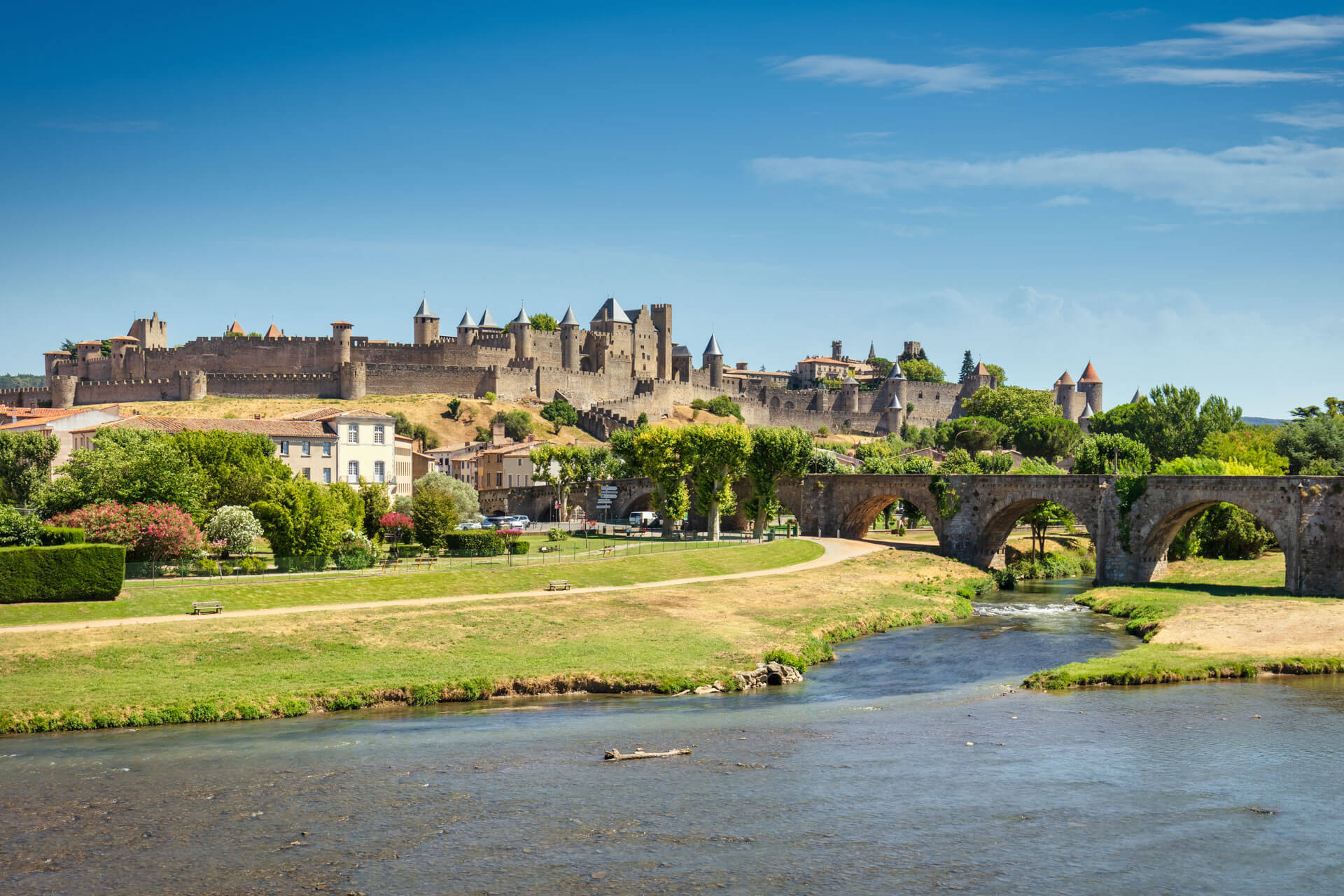 Blick auf die mittelalterliche Festung Carcassonne mit Steinbrücke und Fluss im Vordergrund.