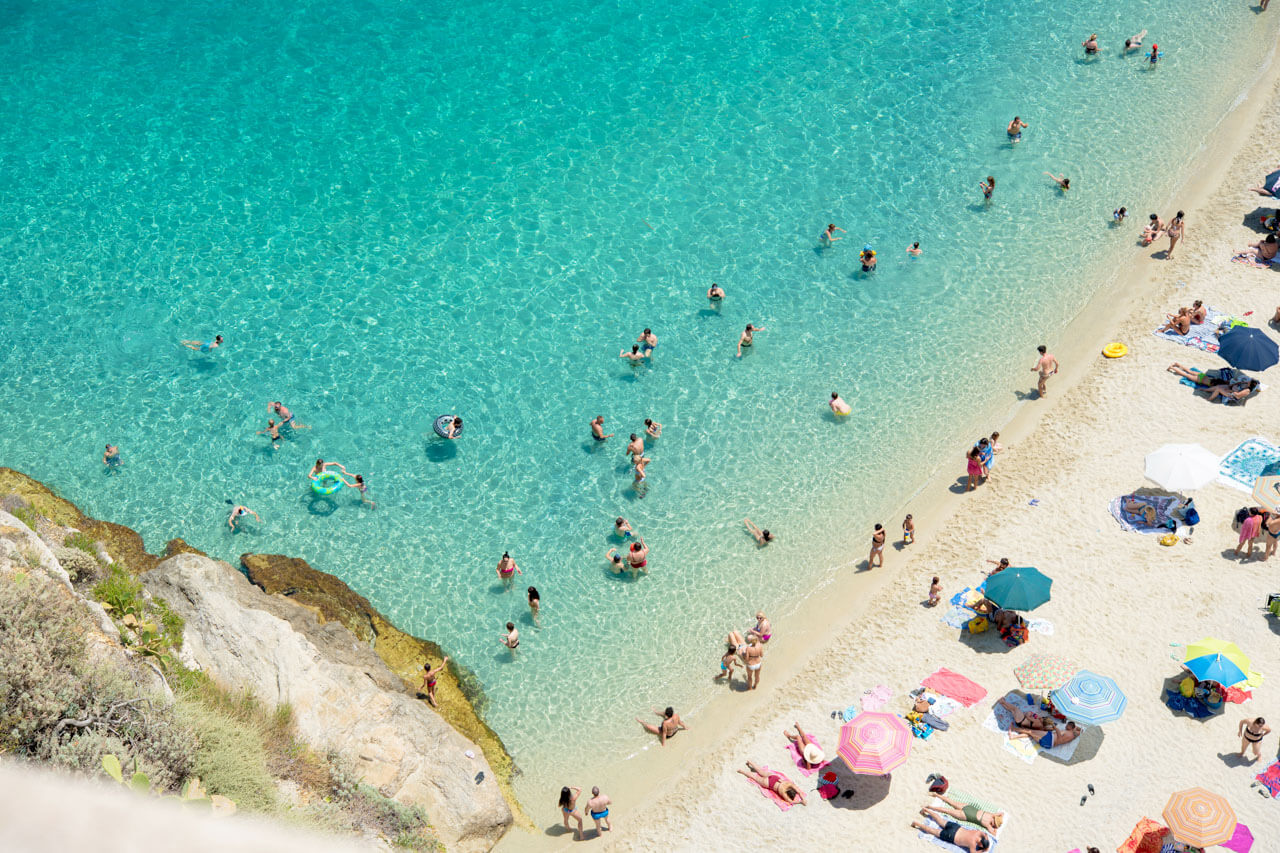 Badende Menschen im türkisblauen Wasser am Strand von Tropea, Italienisch lernen am Meer