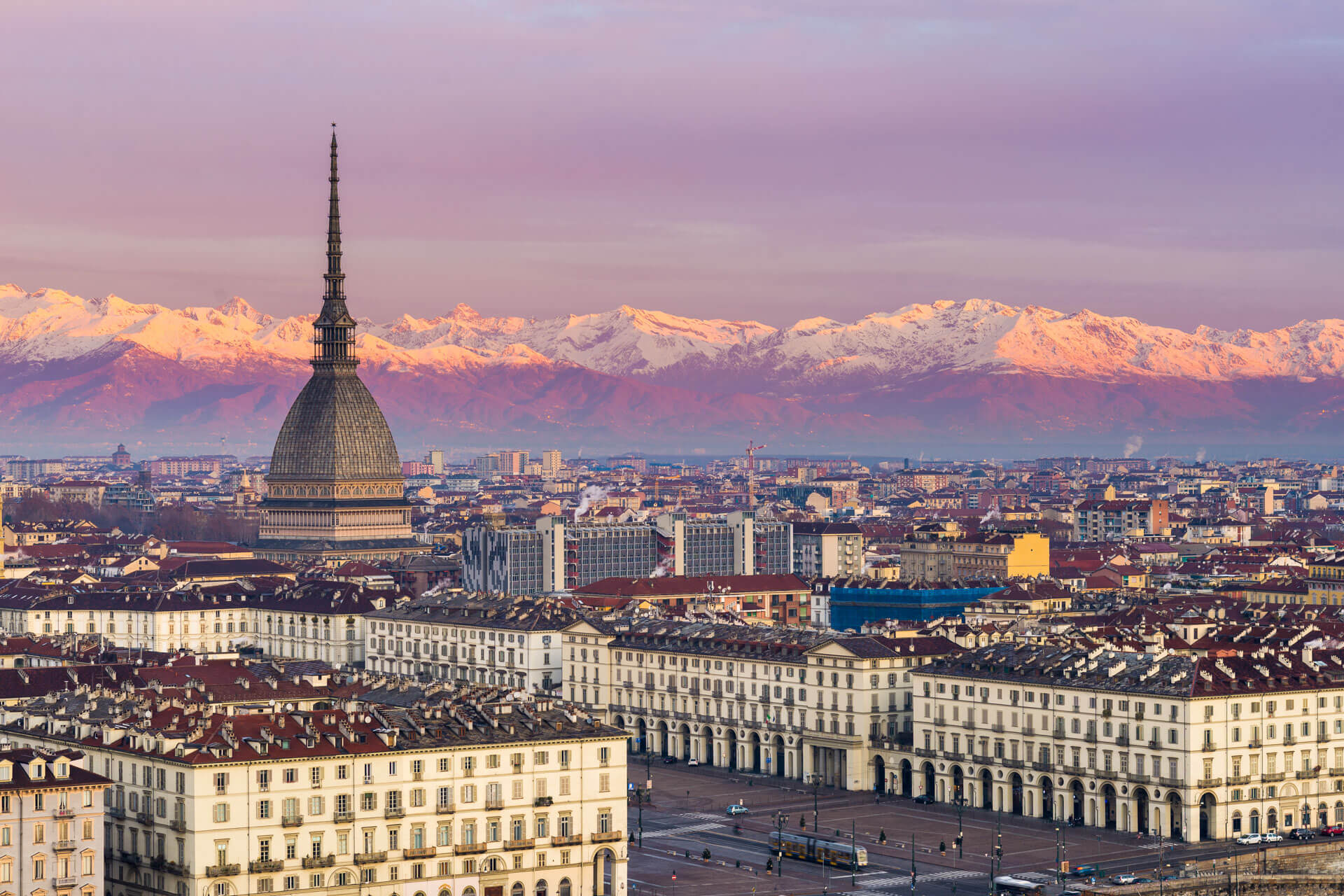 Stadtbild mit Mole Antonelliana und Alpen im Hintergrund bei Sonnenuntergang, ideal für eine Sprachreise nach Italien