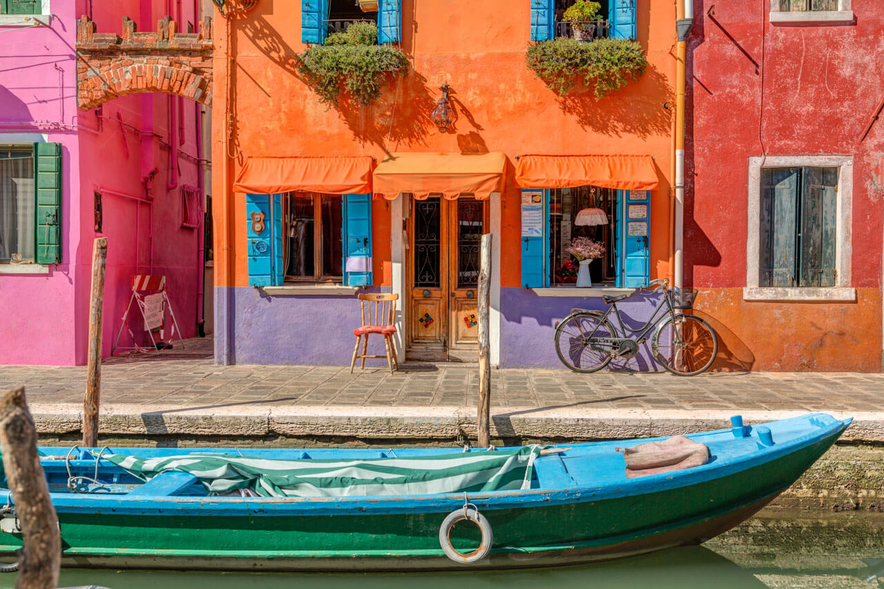 Bunt gestrichene Häuserfront mit blauem Fensterladen und Boot auf Burano – Italienisch Sprachkurs in Venedig
