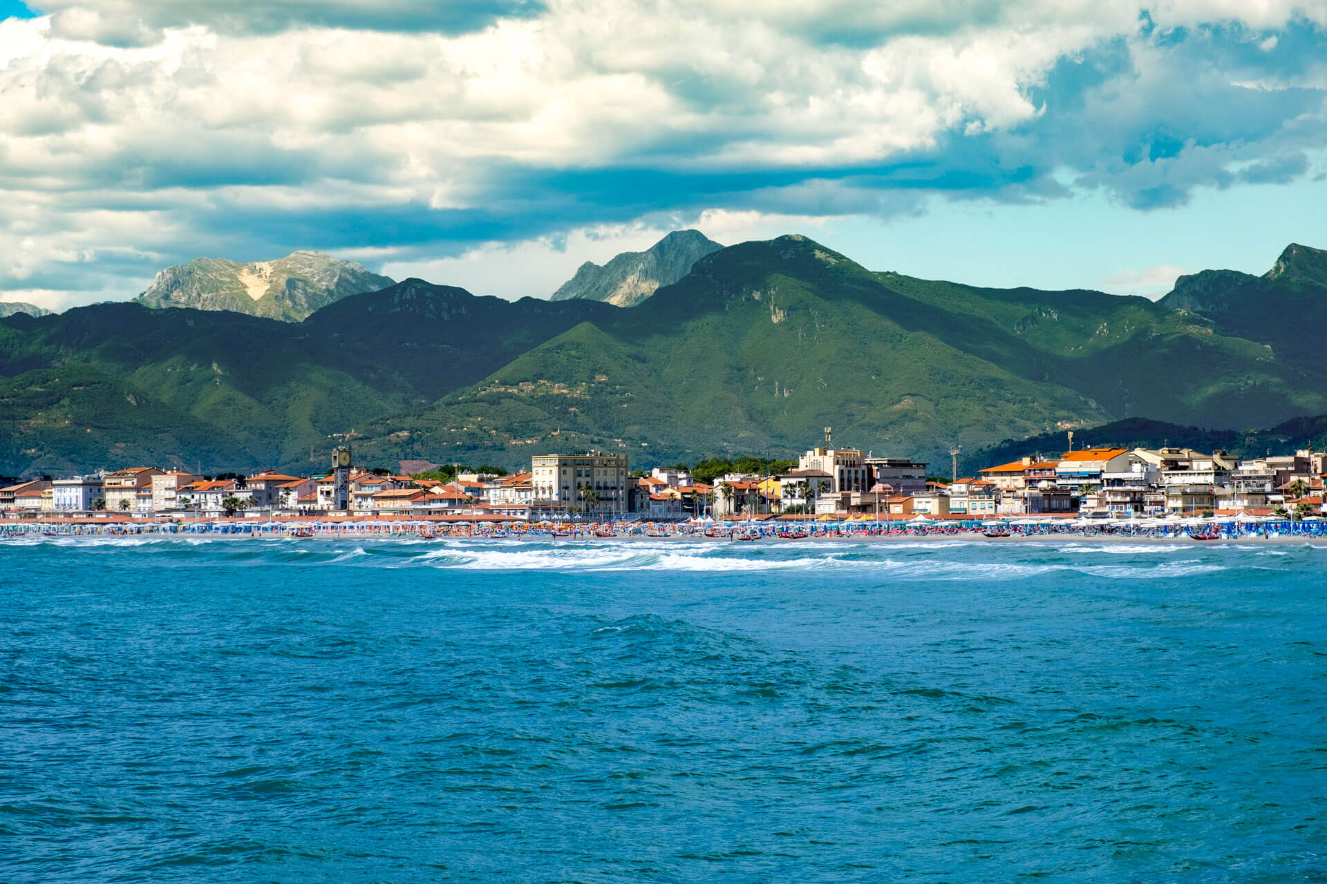 Küstenstadt Viareggio mit Bergen im Hintergrund und Strand am Meer, geeignet für eine Sprachreise Italienisch.
